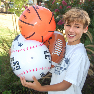 Inflatable sports balls carnival prize held by a boy outdoors